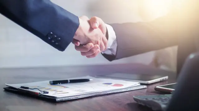 Business owners shaking hands after reaching an agreement on a business sale or ownership transition.